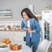 Woman experiencing food intolerance symptoms after eating gluten products.