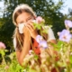 girl with hay fever holding tissue around flowers