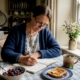 Woman logging food diary at kitchen table