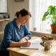 Woman writing food diary at kitchen table