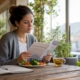 Woman reading food intolerance guide at kitchen table