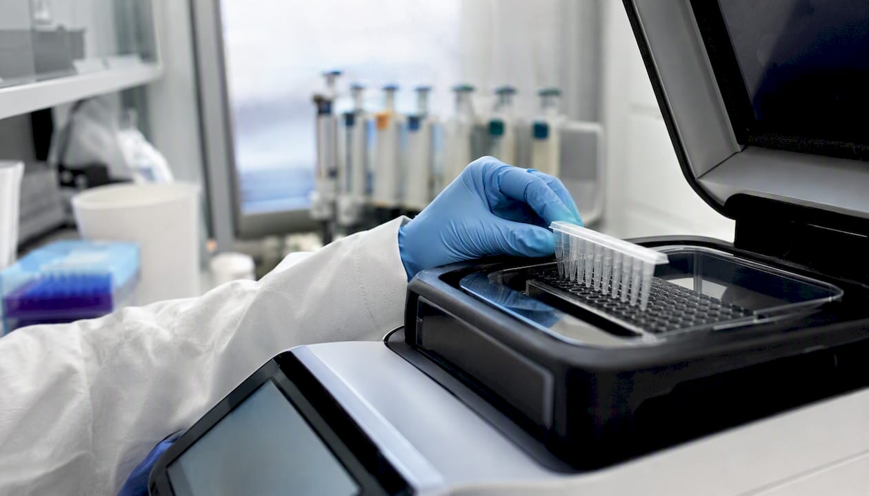 Gloved hand loading samples into PCR machine