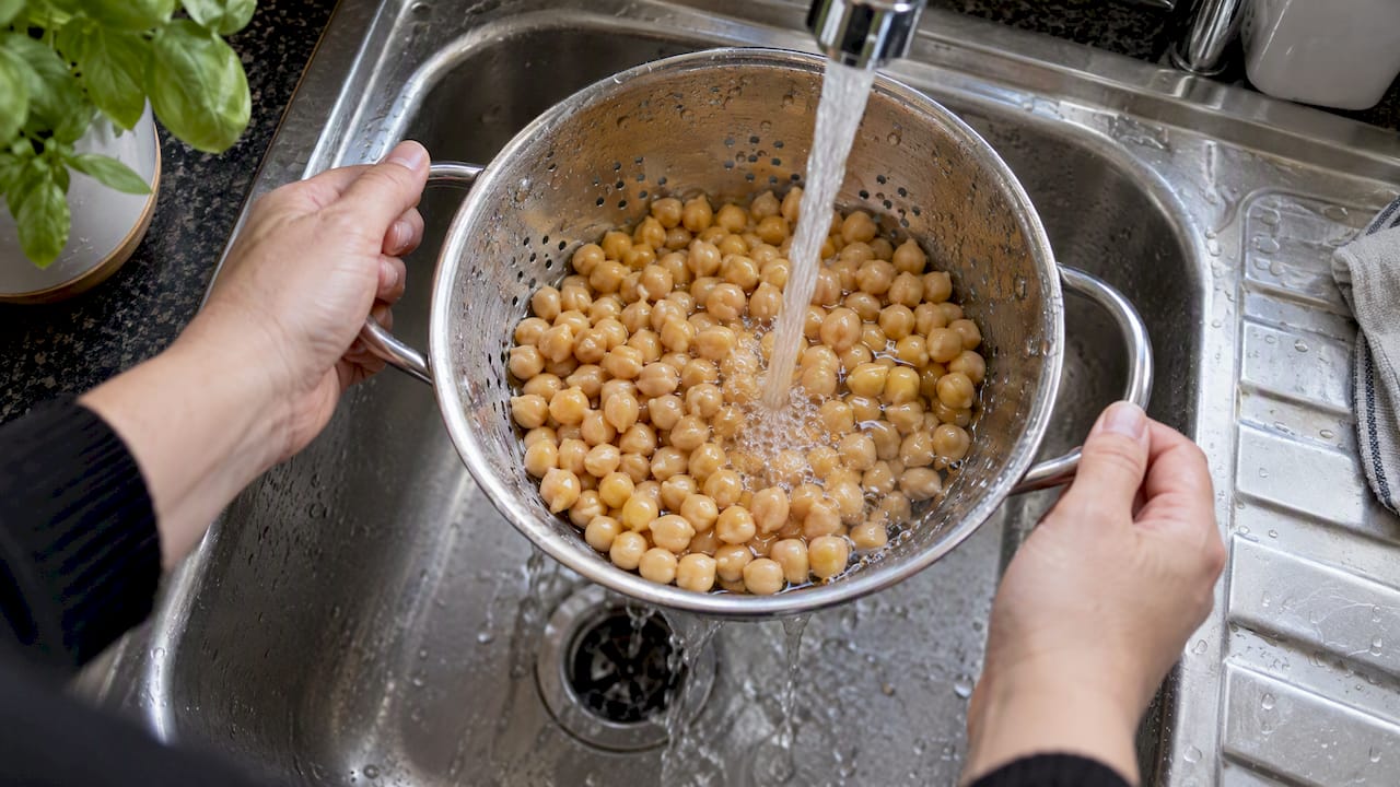 Chickpeas rinsed in a colander at the sink